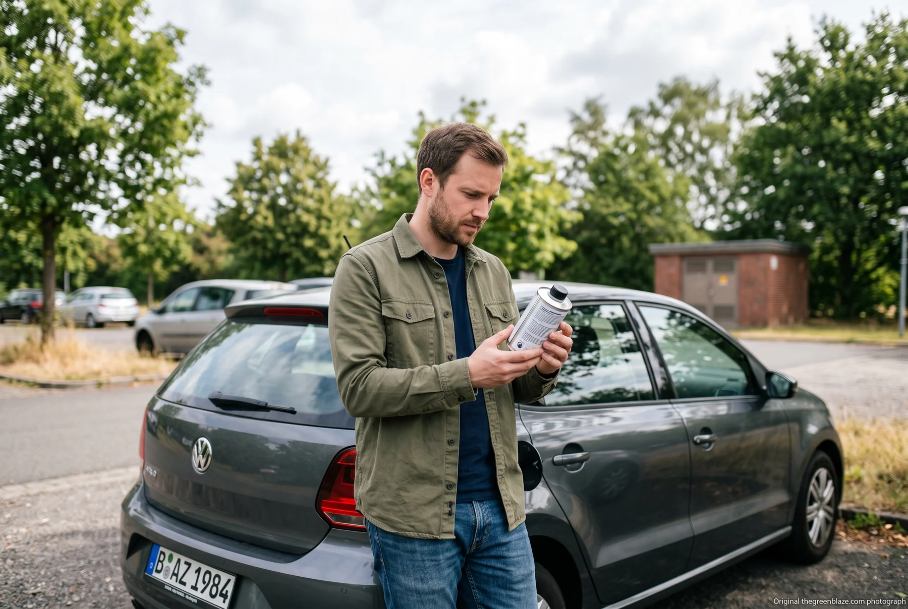 Ein Autofahrer betrachtet eine geschlossene Additivdose neben seinem Fahrzeug.